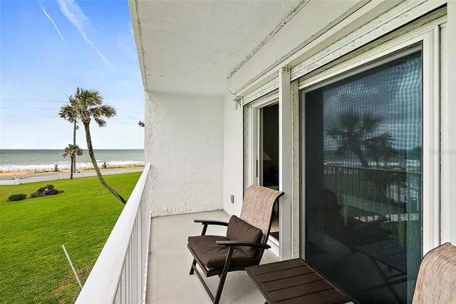 a view of a balcony with furniture and a garden