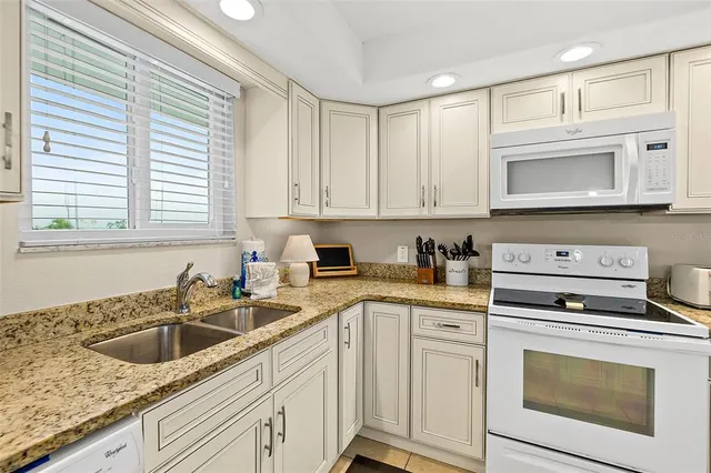 a kitchen with granite countertop white cabinets and white appliances
