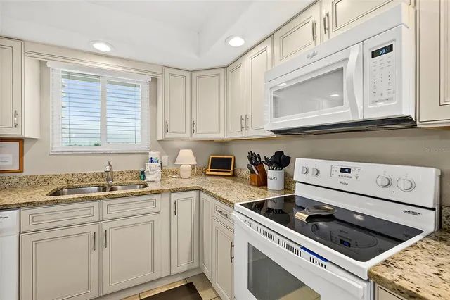 a kitchen with white cabinets a sink dishwasher and a stove with wooden floor