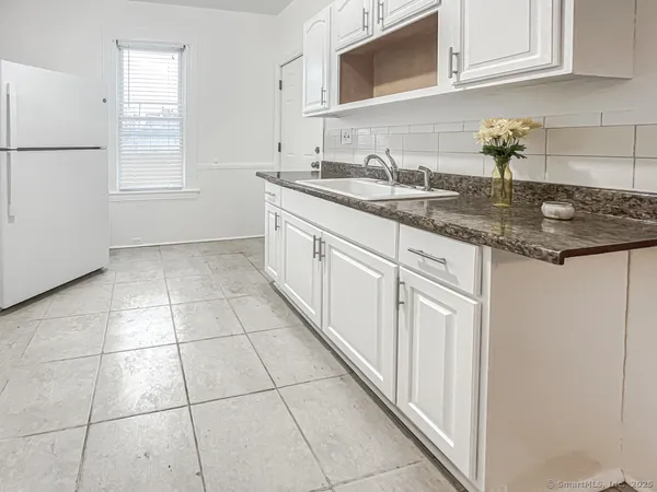 a kitchen with granite countertop white cabinets and white appliances