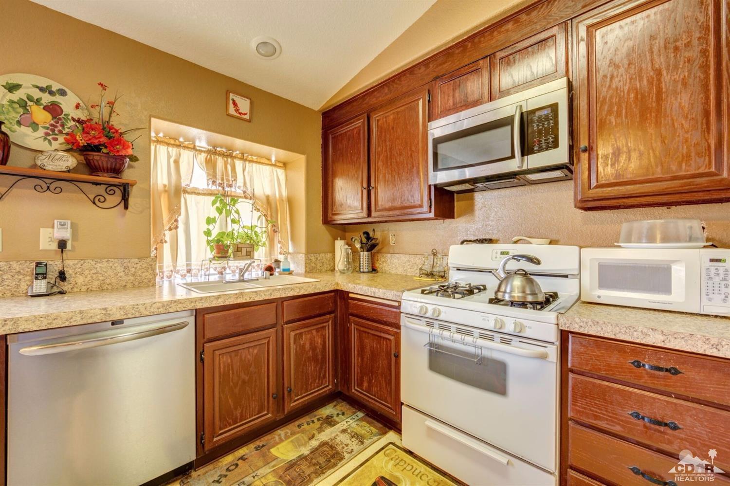 83948 Pacifica Sur Indio, CA 92203 - Photo 3 of 16 a kitchen with stainless steel appliances granite countertop a sink and cabinets with wooden floor