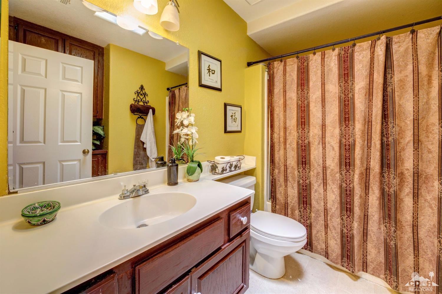 83948 Pacifica Sur Indio, CA 92203 - Photo 9 of 16 a bathroom with a sink a toilet and shower curtain