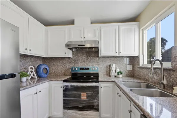 a kitchen with white cabinets and a stove top oven