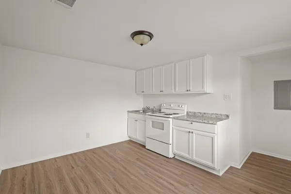 a kitchen with granite countertop a stove cabinets and wooden floor