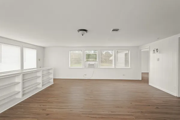 a view of an empty room with wooden floor and a window