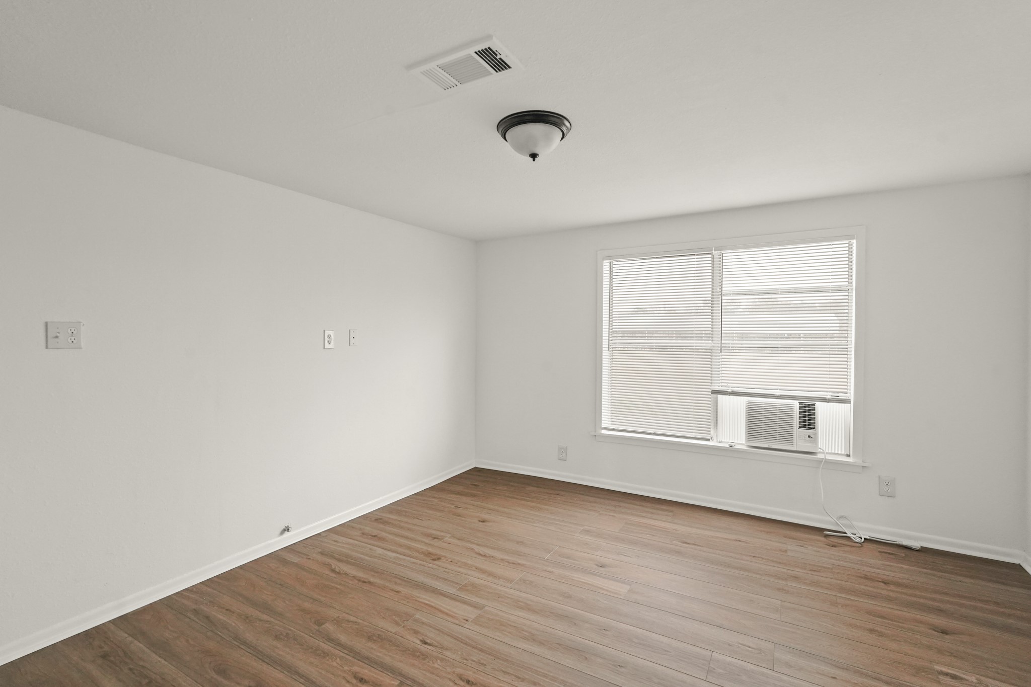 105 West Linney Street, Unit 3 Dayton, TX 77535 - Photo 6 of 12 an empty room with wooden floor and windows
