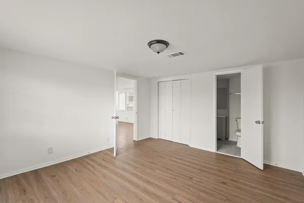 a view of an empty room with wooden floor and closet