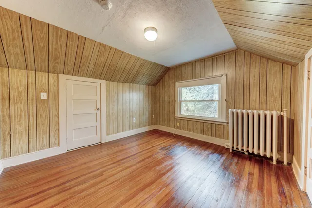 an empty room with wooden floor windows and entrance