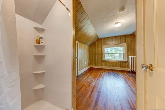a view of a hallway with wooden floor and a bathroom
