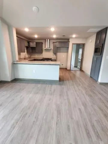 a large kitchen with stainless steel appliances granite countertop a large counter top and a wooden floor