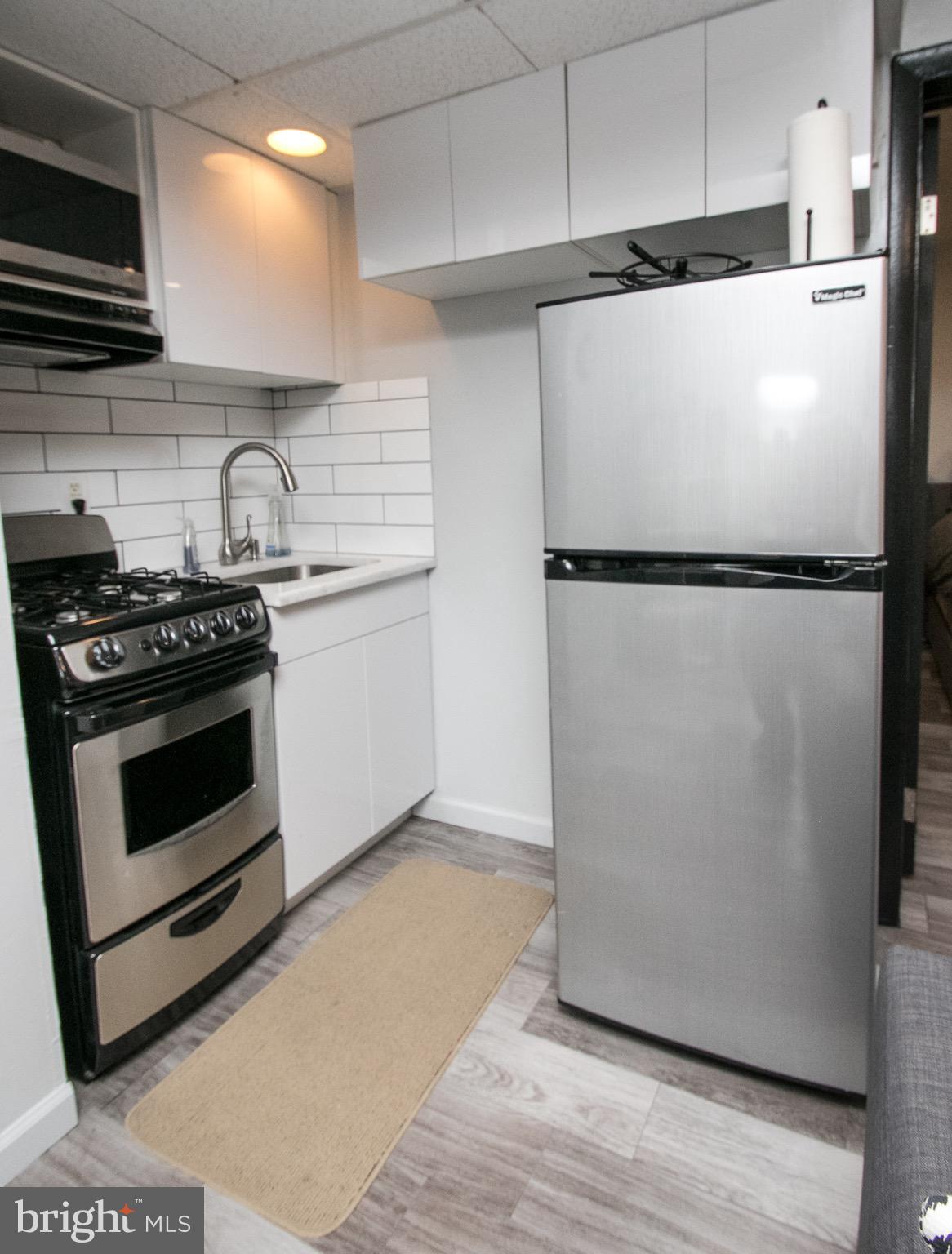2135 Walnut Street, Unit 304 Philadelphia, PA 19103 - Photo 3 of 5 a white refrigerator freezer and a stove sitting inside of a kitchen