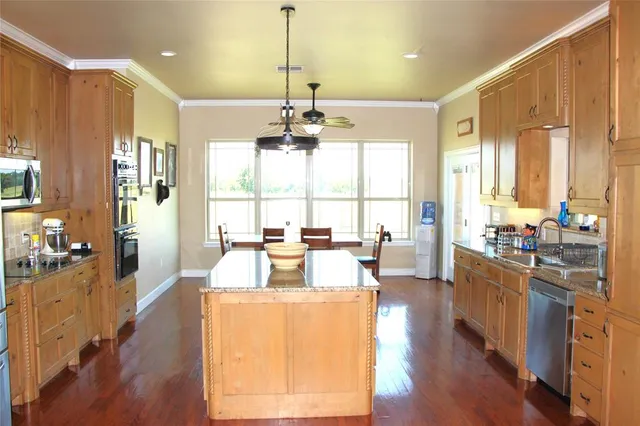 a living room with stainless steel appliances granite countertop furniture wooden floor and a chandelier
