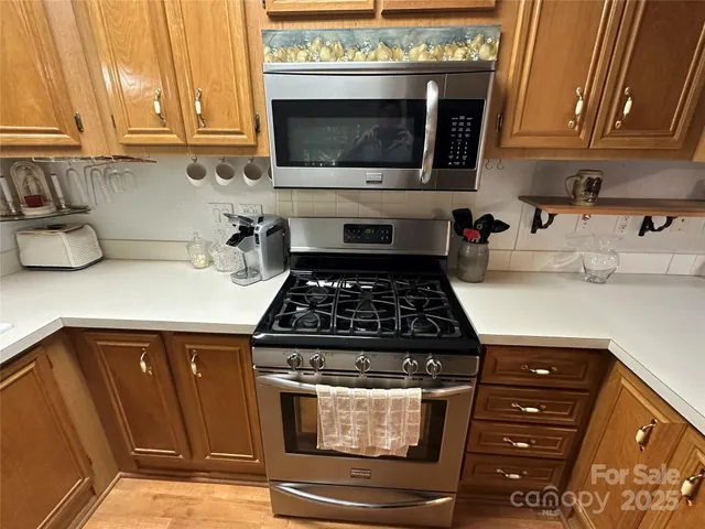 a kitchen with stainless steel appliances granite countertop a stove a sink and a microwave