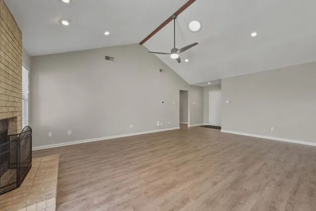 an empty room with wooden floor and ceiling fan