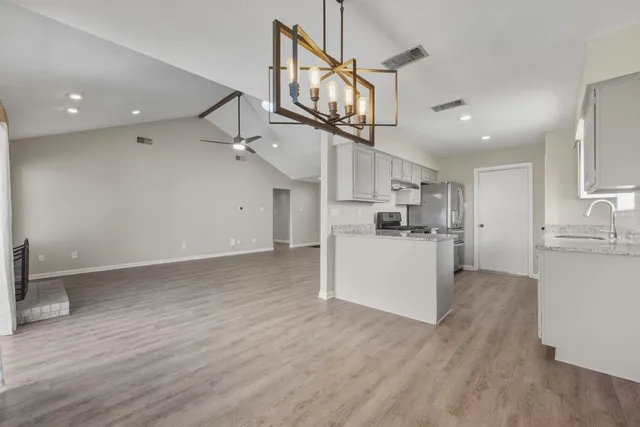 an empty room with wooden floor ceiling fan and windows