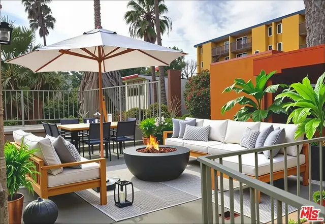a view of a patio with couches table and chairs under an umbrella