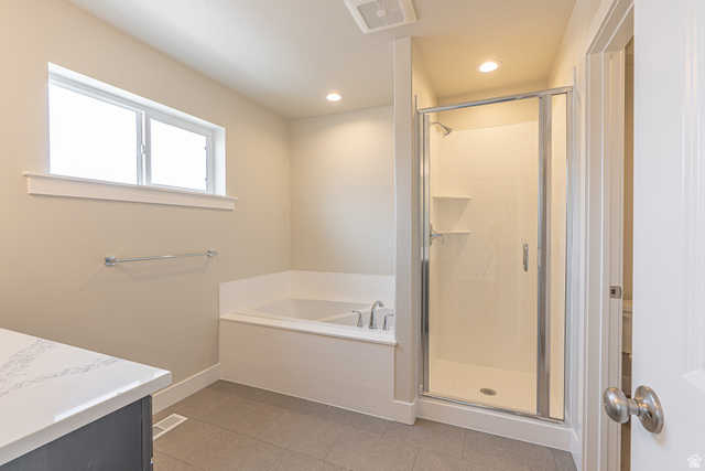 2249 South 1090 West, Unit 76 Nibley, UT 84321 - Photo 17 of 19 Bathroom featuring a built-in soaking tub with deck-mounted fixtures, a glass-enclosed shower with integrated shelving, and a vanity with a light-toned countertop