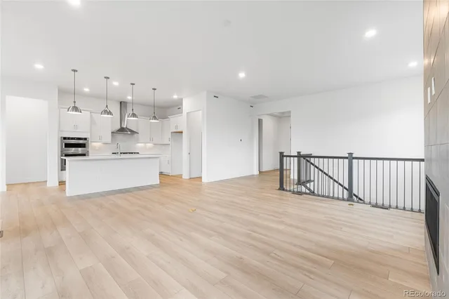 a view of a kitchen with kitchen island a sink wooden floor and a refrigerator