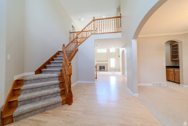 598 Hollow Creek Road Draper, UT 84020 - Photo 18 of 110 Two-story foyer featuring a grand staircase with wood newel posts and spindles, carpeted treads, and light wood-finish flooring