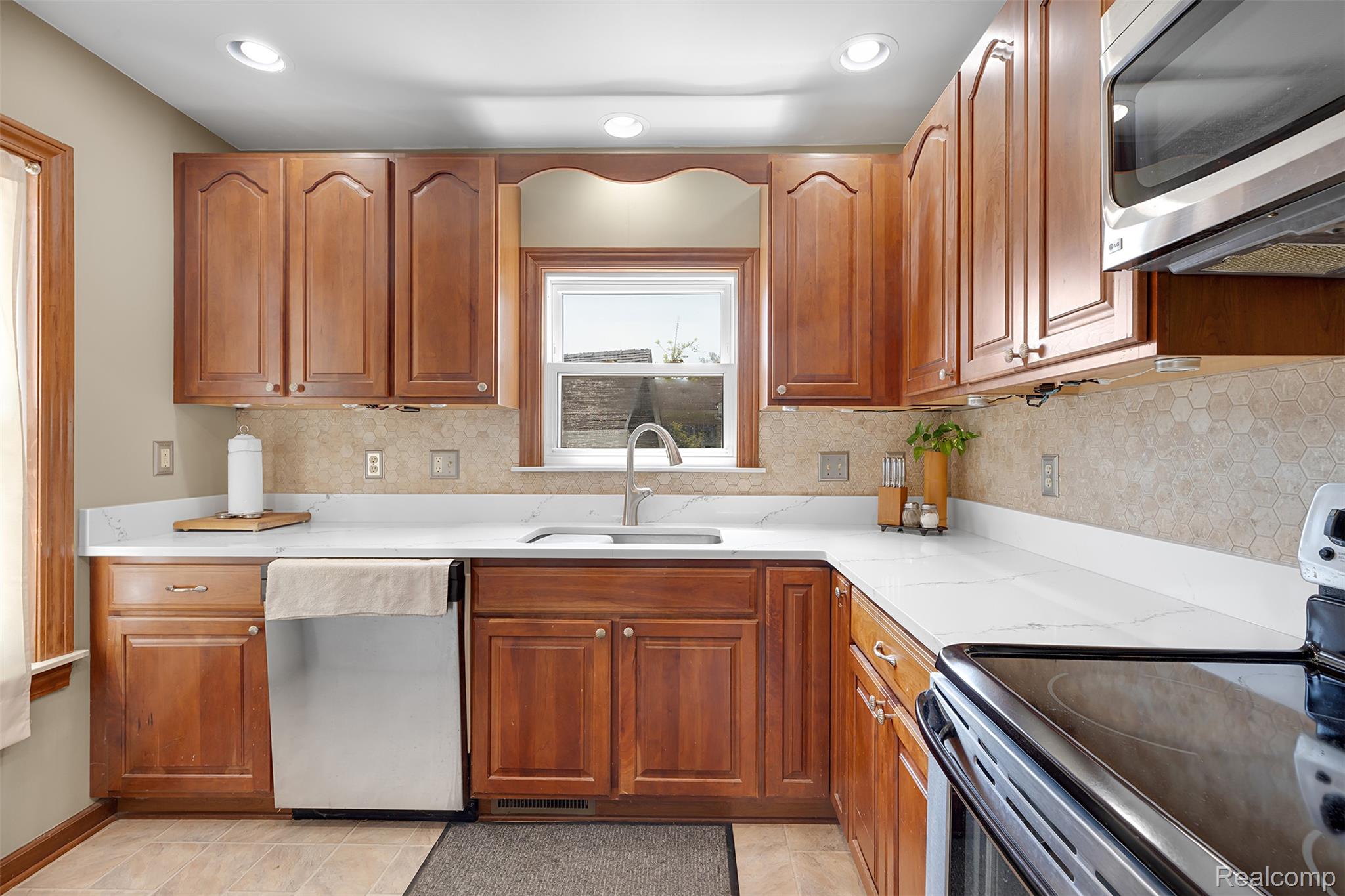 22827 Meridian Road Grosse Ile, MI 48138 - Photo 22 of 36 Kitchen with stainless steel appliances, tasteful backsplash, wood finish cabinets, recessed lighting, and light stone countertops