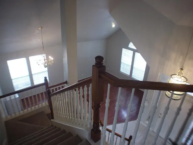 a view of staircase with railing and a chandelier
