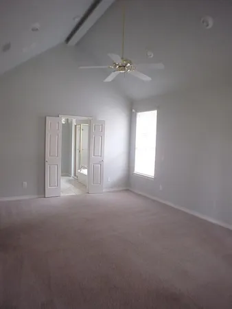 an empty room with windows and ceiling fan