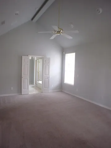 an empty room with windows and ceiling fan
