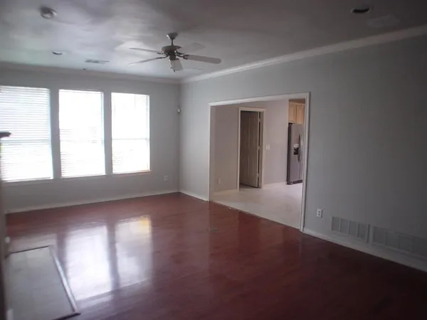 an empty room with wooden floor chandelier and windows