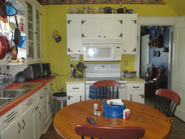 a kitchen with stainless steel appliances kitchen island granite countertop a table chairs and a wooden floor