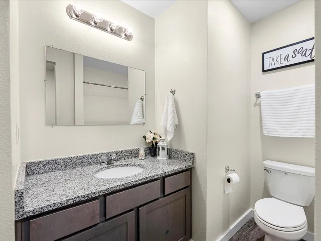 a bathroom with a granite countertop sink a toilet and a mirror