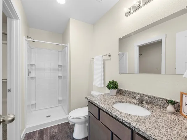 a bathroom with a granite countertop sink a toilet and shower