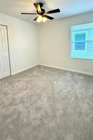 an empty room with a ceiling fan and wooden floor