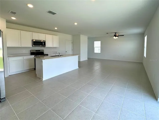 a living room with stainless steel appliances kitchen island granite countertop a sink and cabinets