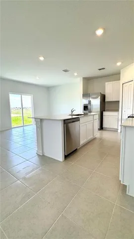 a large white kitchen with a stove a sink a counter top space and cabinets