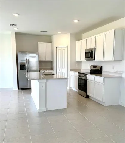 a kitchen with granite countertop a sink a counter top space stainless steel appliances and cabinets