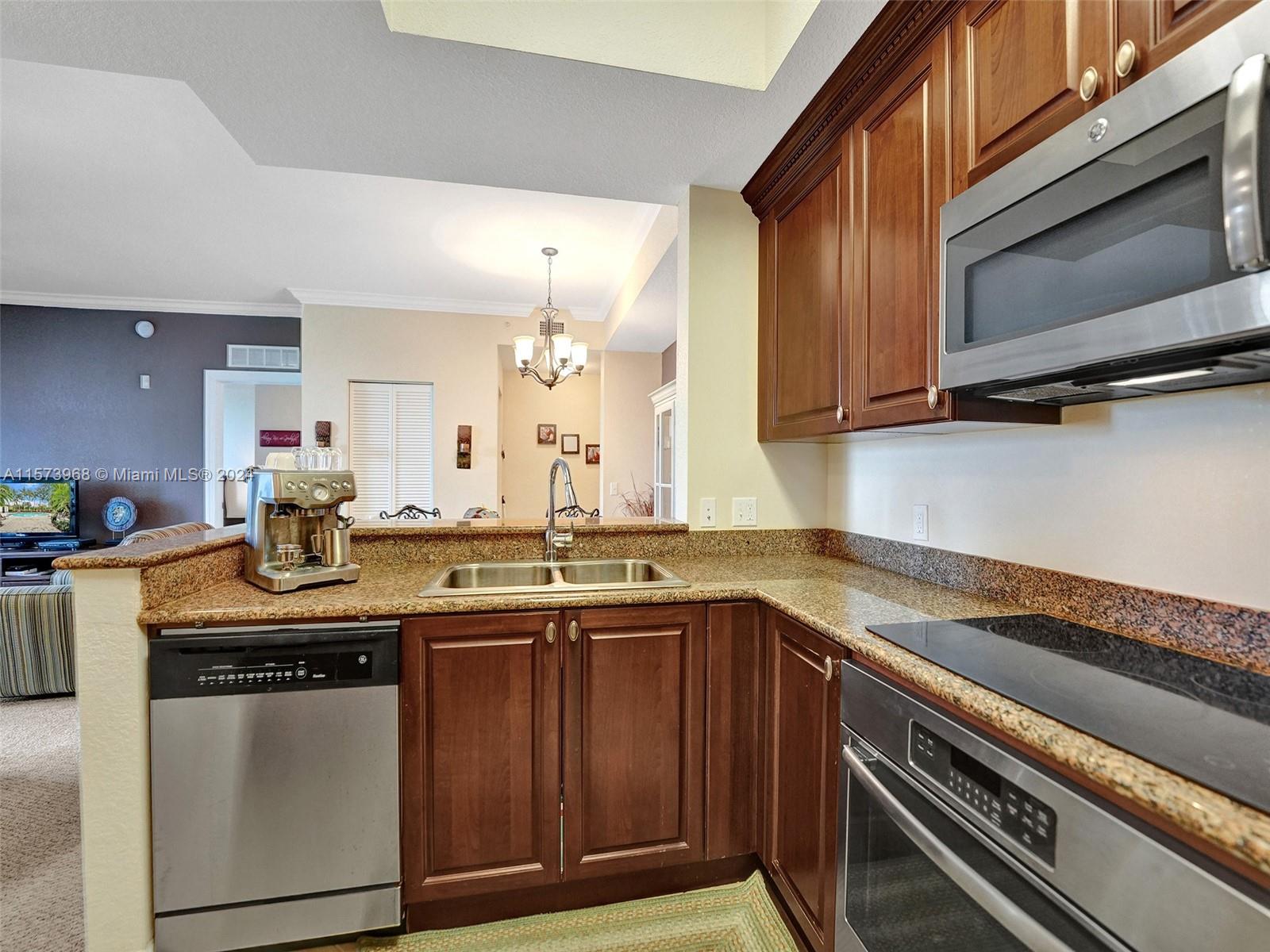 1660 Renaissance Commons Boulevard, Unit 2508 Boynton Beach, FL 33426 - Photo 5 of 28 a kitchen with stainless steel appliances granite countertop a sink stove and microwave