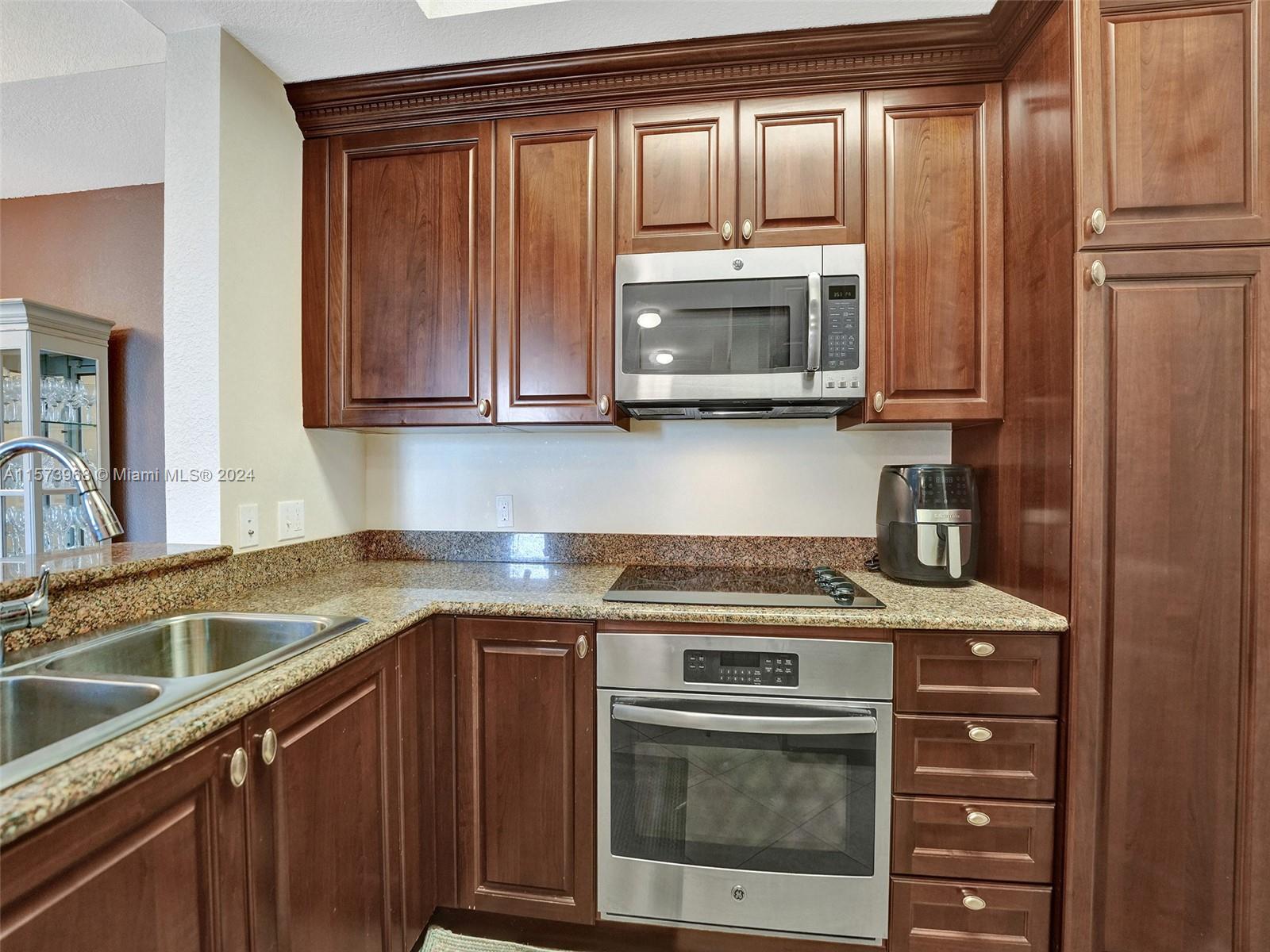 1660 Renaissance Commons Boulevard, Unit 2508 Boynton Beach, FL 33426 - Photo 6 of 28 a kitchen with granite countertop a sink stove and microwave