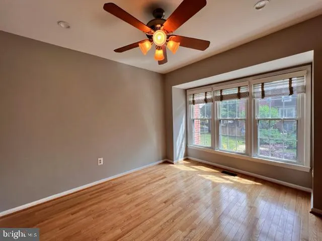 a view of an empty room with wooden floor and a chandelier