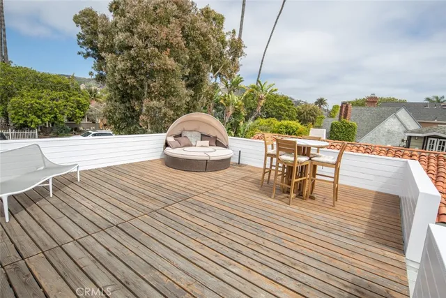 a view of a roof deck with table and chairs a barbeque with wooden floor and fence