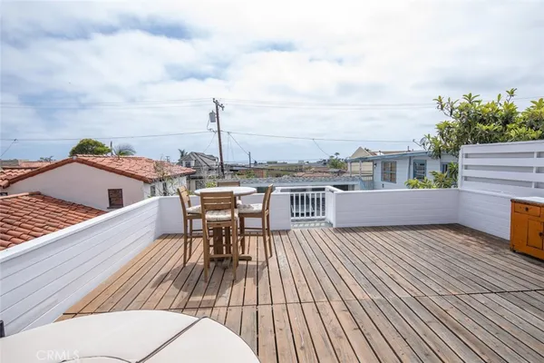 a view of a roof deck with table and chairs a barbeque with wooden floor and fence