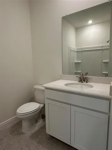 a bathroom with a granite countertop toilet sink and mirror