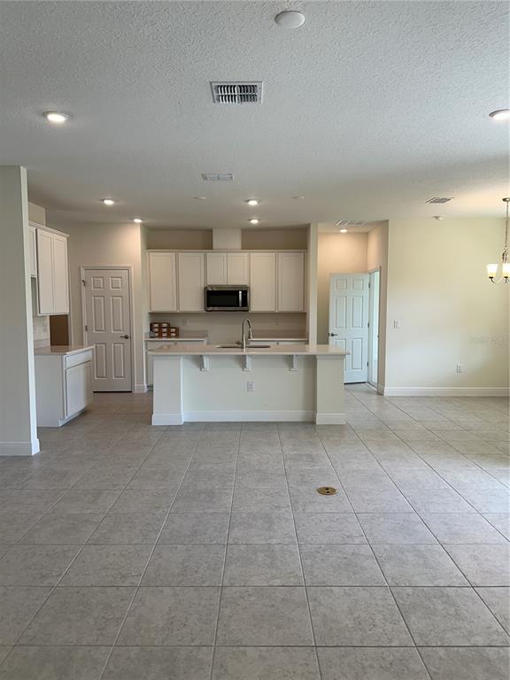 6107 Southwest 115th Street Road Ocala, FL 34476 - Photo 2 of 16 a large white kitchen with kitchen island a stove a refrigerator and white cabinets with wooden floor