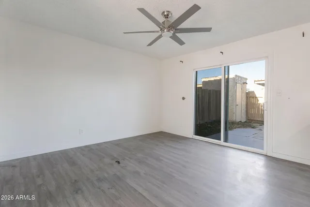 an empty room with wooden floor and a ceiling fan