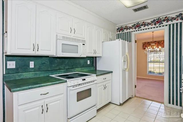 a kitchen with granite countertop white cabinets and white appliances