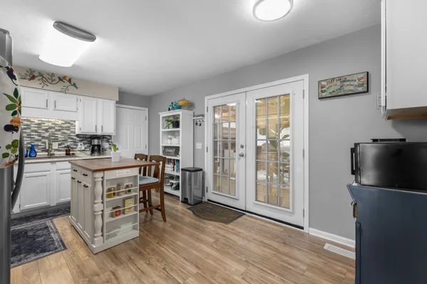 a kitchen with stainless steel appliances a refrigerator a stove a sink and white cabinets with wooden floor