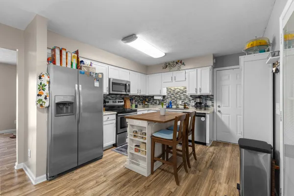 a kitchen with stainless steel appliances a refrigerator a stove a sink dishwasher and a dining table with wooden floor