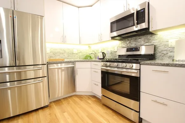 a kitchen with stainless steel appliances granite countertop a stove microwave and refrigerator