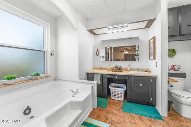 a spacious bathroom with a tub sink and mirror