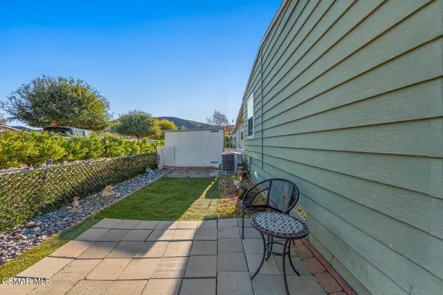 a view of a chair and table in the backyard with potted plants