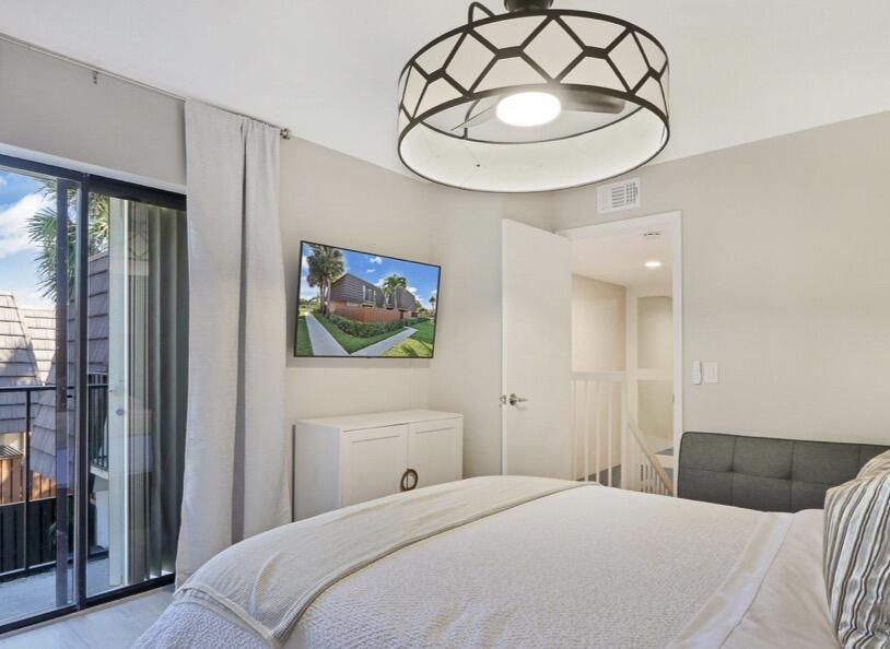 2117 21st Court Jupiter, FL 33477 - Photo 9 of 10 a bedroom with a bed and a chandelier